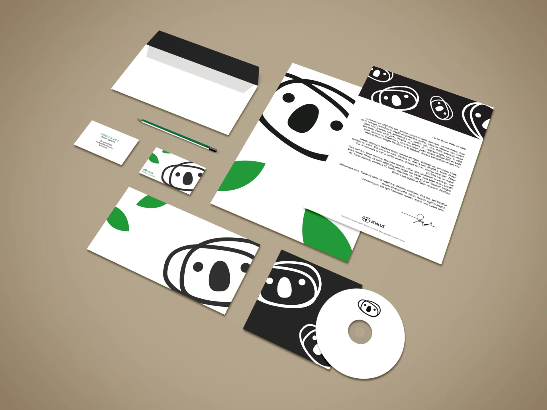 Mockup original de la papelería Koalus: carta, sobres, tarjetas y disco con el koala negro y hojas verdes.